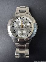 Front view of vintage men's Guess quartz watch showing silver-tone metal case, numbered dial with three subdials, and metal link bracelet.