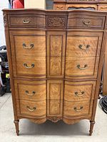 Front view of five-drawer chest dresser showing curved drawer fronts and brass-tone bail handles.