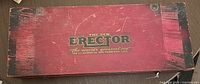 Top view of red wooden box with black corner accents, 'The New Erector' logo in gold and black lettering.