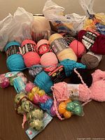 Top view of mixed yarn skeins with colorful plastic Easter eggs bags in plastic bags on a wooden surface.