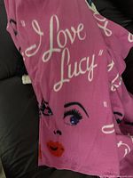 Close-up photo of pink I Love Lucy Snuggie showing face and text