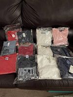 Multiple vintage shirts folded and bagged showing assortment of colors and styles, many with tags.