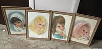 Four framed mid-century Northern Bath Tissue baby portrait prints leaning against a wall