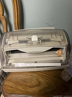 Side view of manual ezLaminator laminator on wooden chair showing transparent cover and white body.