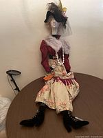 Full view of large vintage boudoir doll seated on table showing entire outfit and boots