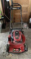 Front view of red Toro Recycler lawn mower with black handle. Shows overall mower and wheels.