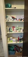 Photo showing multiple shelves of a linen closet containing towels, personal care products, and medicine boxes