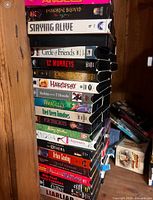 Stack of about 22 VHS tapes showing titles including Angel Heart, Immortal Beloved, Staying Alive, Circle of Friends, 12 Monkeys, Lord of the Rings, Hairspray, Robin Hood and others.