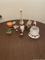 Photo showing all 13 small vintage figurines and collectibles arranged on a table.