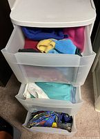 Plastic storage cart with three drawers filled with assorted colorful fabric pieces