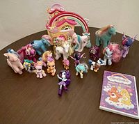Overview of all My Little Pony figurines in multiple colors and a Care Bears DVD on table.