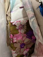 Floral fabric with large flowers in pink and purple on green background inside plastic tub