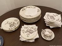 Full lot overview showing stack of dinner plates, salad plates, bread plates, numerous saucers, and one demitasse cup with saucer.