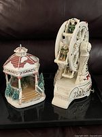 Photo showing ceramic Ferris wheel music box next to fiber optic gazebo on table.
