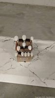 Wooden stand holding measuring spoons with white handles arranged on marble surface