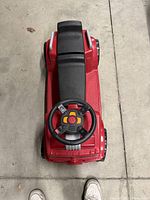Top-down photo of the kids ride-on fire truck showing the black seat, steering wheel with buttons, and red body.