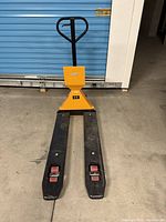 Front view of Uline pallet jack showing yellow mast, black handle and forks