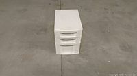 White plastic drawer unit front view on floor.