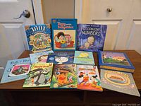 Overview photo of all twelve children's books on a dark table including titles and visible artwork