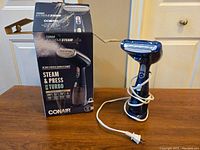 Conair Turbo Extreme Steam handheld steamer with original box on a wooden surface, showing device and power cord.