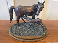 Front angle view of the bronze finish mare and foal sculpture showing detail of both statues on a textured base.