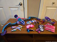 Photo showing Nerf bow, colorful darts, flying disks, small toy gun, and suction tip darts on a wooden table
