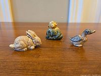 Photo showing the three ceramic animal figurines (rabbit, monkey, and duck) arranged on a wooden surface.