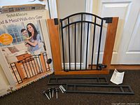 Gate with wooden side panels, black metal gate section with arched top, hardware, manual, and original box displaying product image.