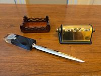 Photo showing the three items on a wooden surface: the wooden card holder, brass desk calendar, and nickel letter opener.