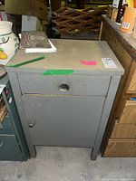 Front view of the gray metal filing cabinet showing drawer and door, measuring about 20x16x31 inches, with scuffs and scratches on surface.