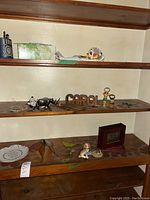 Shelf with multiple small animal figurines, a wooden 'CAROL' bottle opener, a TY Snoopy figurine, and a ceramic decorative bowl.