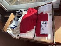 Folded Hopkinton flag and red, white, and blue bunting with grommets in a box by a window.