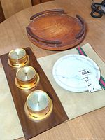 Photo showing the wooden lazy susan with visible engraved markings alongside the home weather station with brass dials and round marble base.