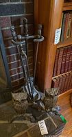Wide view showing both owl andirons with fireplace tool stand and tools next to brick hearth