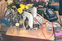 Workbench with various power tools including circular saw, drills, jigsaw, orbital sander, and containers with drill bits.