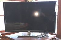 Front view of RCA 31-inch LED television showing the screen, bezel, and remote on stand.