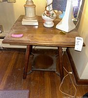 Front view of the wooden side table showing square top, four legs, and lower cross stretcher with visible wear and scratches.