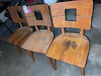 Three vintage solid wood chairs arranged side by side showing overall wear and condition.