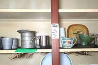 Shelving unit with vintage kitchen items: tin measuring cups, mini sifter, Pyrex measuring cup, English Ironstone pitcher, lusterware creamer with chip.