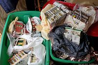 Two plastic bins filled with bagged ceramic buildings and wired light cords