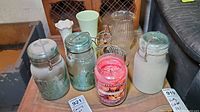 Overview of all items on a wooden table showing canning jars, vases, candle, metal cat figurine, and glass pitcher.