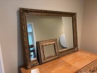 Photo showing both mirrors side by side on a flat surface, large mirror about three times the size of smaller mirror.