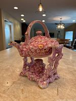 Porcelain tea set with floral design shown assembled, highlighting the teapot on stand.