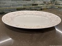 Cream-colored ceramic turkey platter showing intricate raised botanical border design.