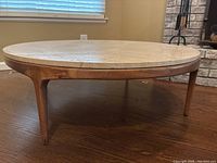 Side profile view of round coffee table showing wooden base and marble top