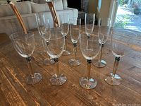 Set of 10 glasses including 4 water goblets and 6 champagne flutes arranged on wooden table.