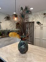 Full view of raku vase with feathers and voodoo doll in kitchen setting