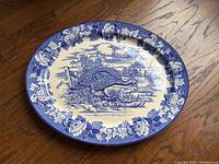 Top-down view of oval blue and white porcelain platter with detailed turkey scene and floral border.