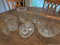 Full lot displayed on wooden table showing two vases, candy jar with lid, sugar and creamer set on platter, and bowl.