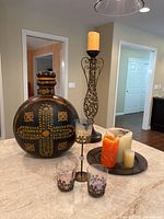 Photo showing large round painted vase with lid, metal candle holders with glass cups decorated with metal snowflakes, and metal plate with assorted pillar candles.